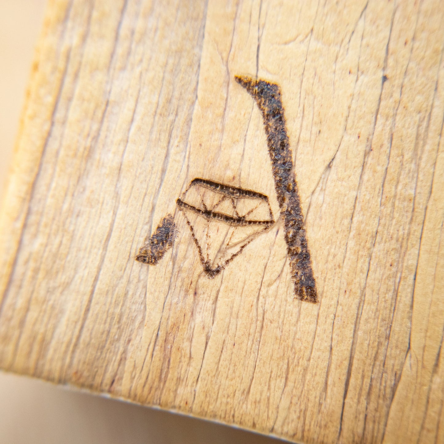 A laser engraved logo of a capital letter A and a diamond on a surface of water hyacinth vegan leather.