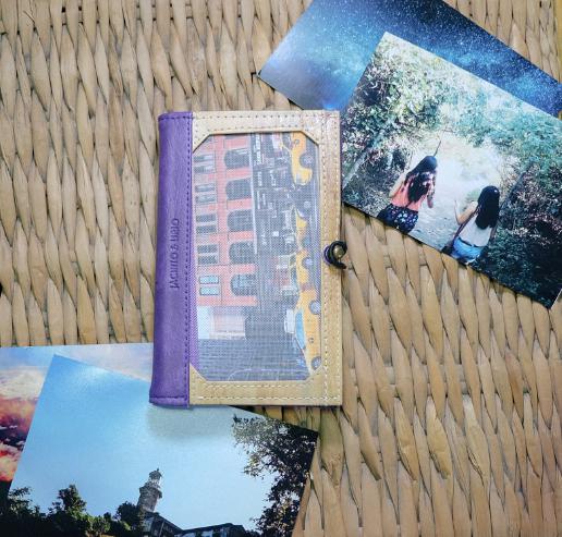A vegan leather notebook with a picture frame in its cover, laid on a surface amongst other photos.