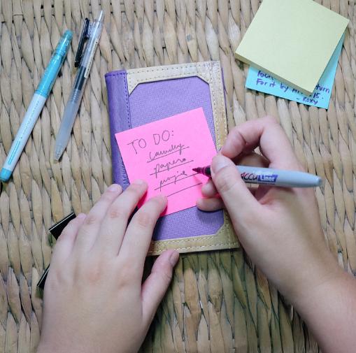 Writing a post-it note on a Pinto Mini Personalizable Passport Holder, highlighting its practical and versatile design.