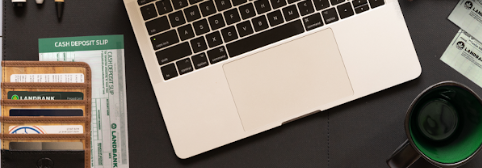 cropped image of laptop and mug on top of a grey leather work mat with cards and receipts tucked into pockets in the desk work mat.