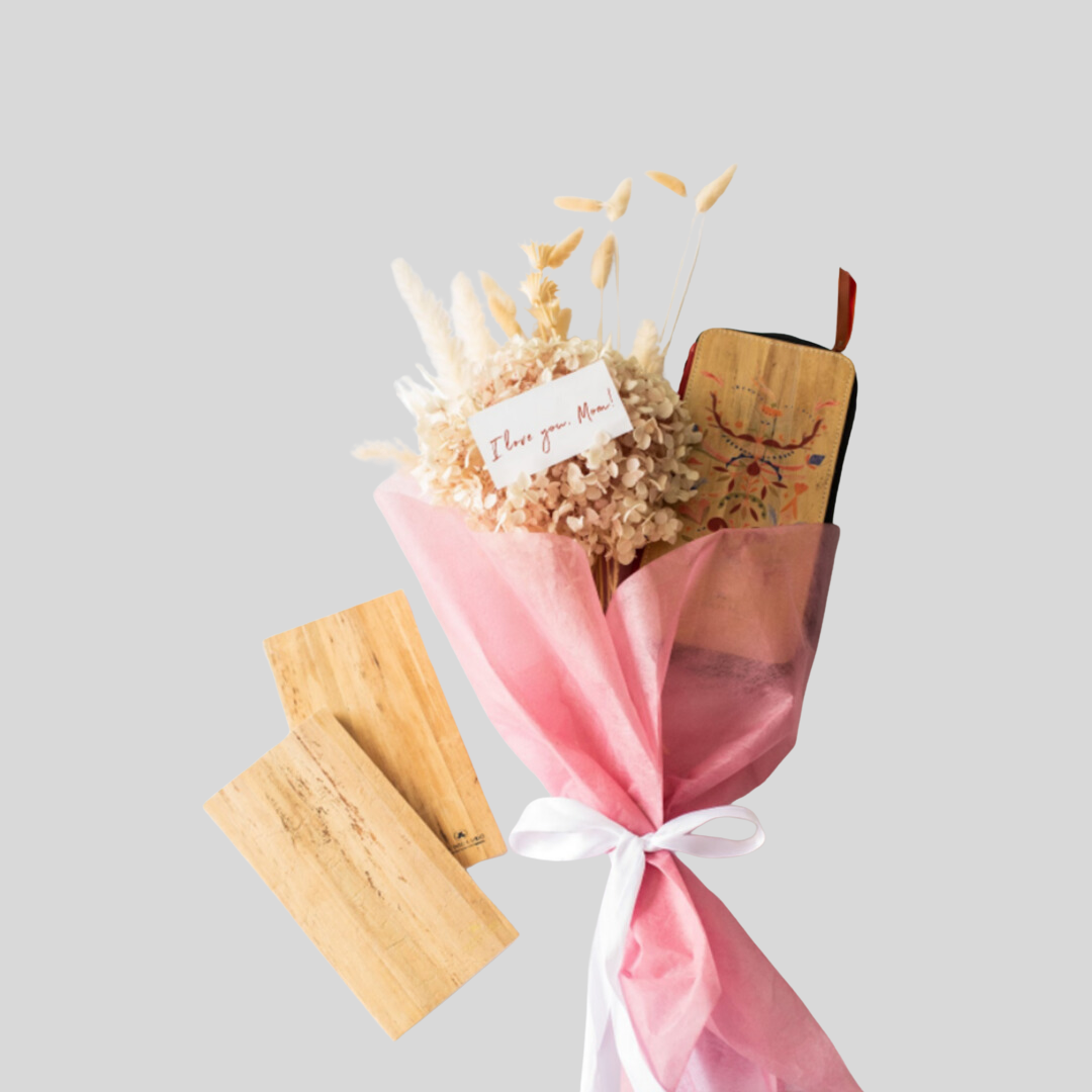 A bouquet of small white flowers containing a zippable vegan leather notebook with two page refills off to the side.