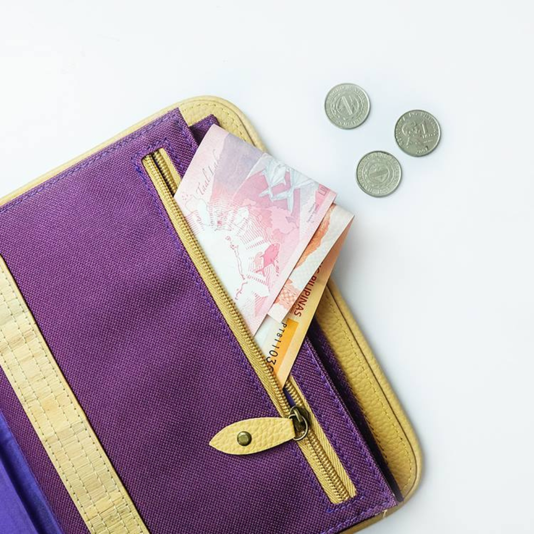 A purple pouch with coins and bills in it that are spilling out