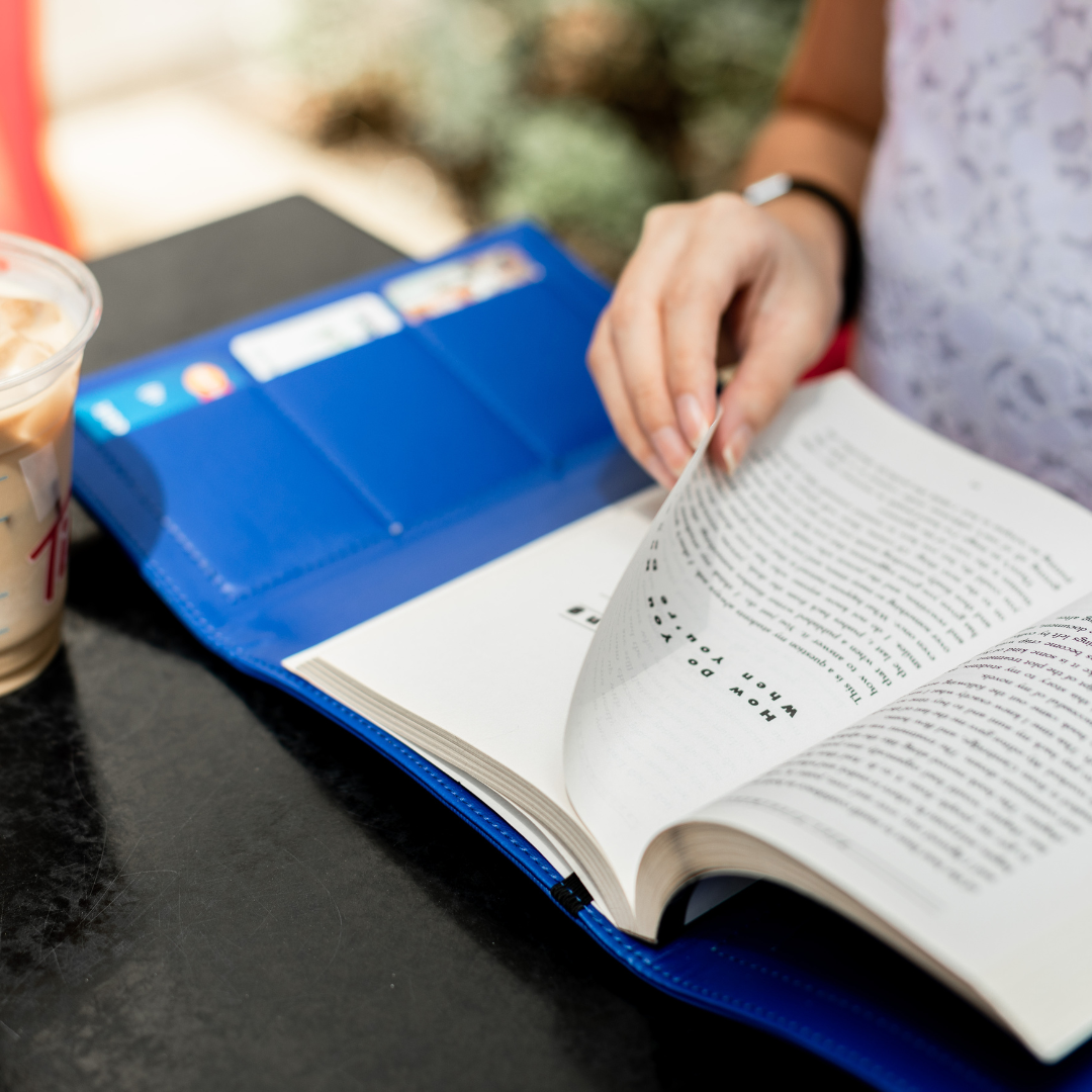 A person flipping through the pages of a blue journal.