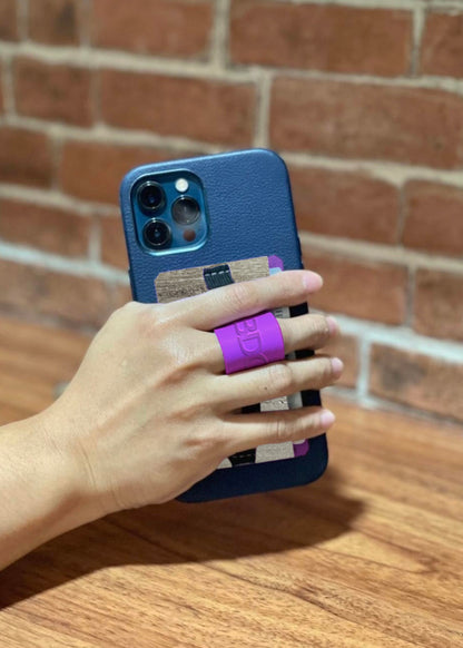 Close-up of a hand holding a phone with a multifunctional cellphone grip and card holder, featuring a purple strap and vegan leather design.