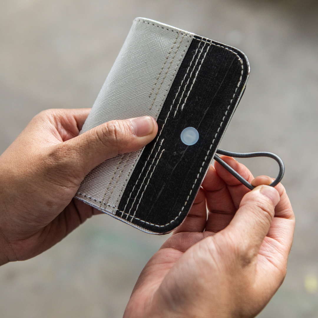 A black and white card wallet with a garter closure.