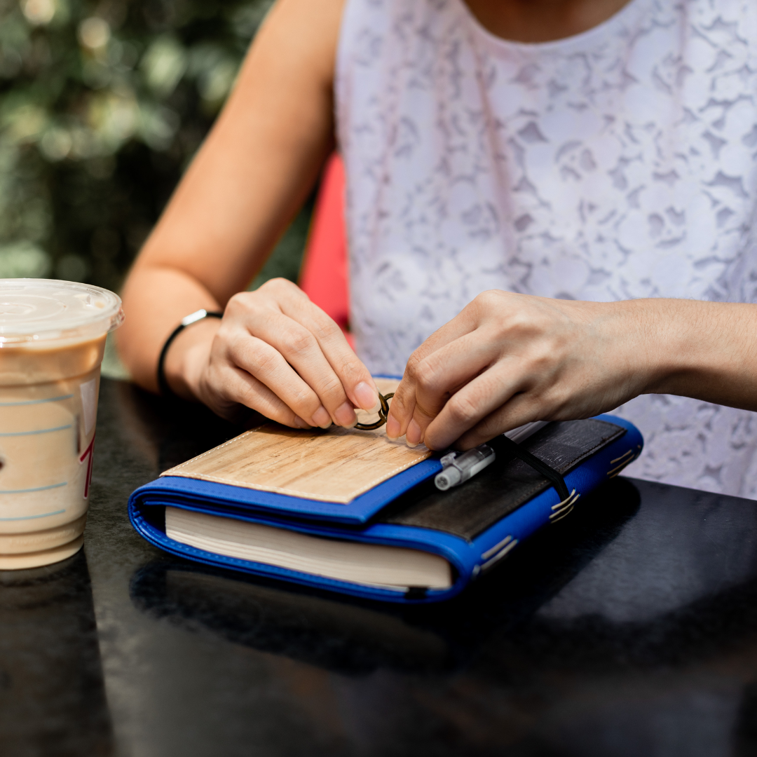 A person tying closed a dual cover blue journal.
