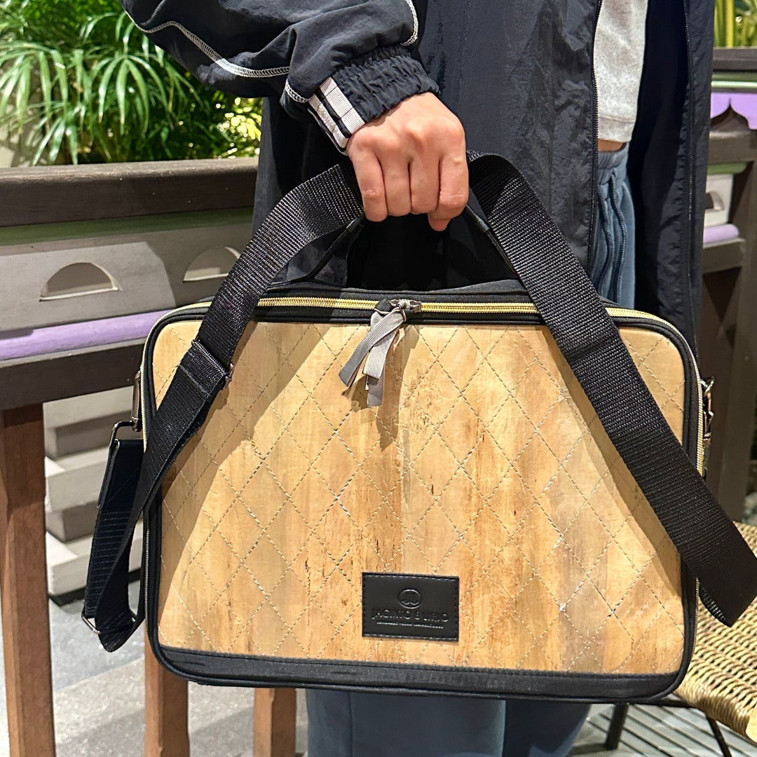 Person holding a Hiraya bag with a strap outdoors.