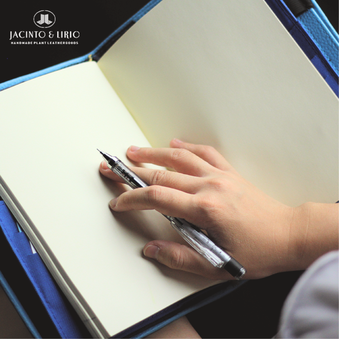 A person holding open a blank journal with a pen in their hand.