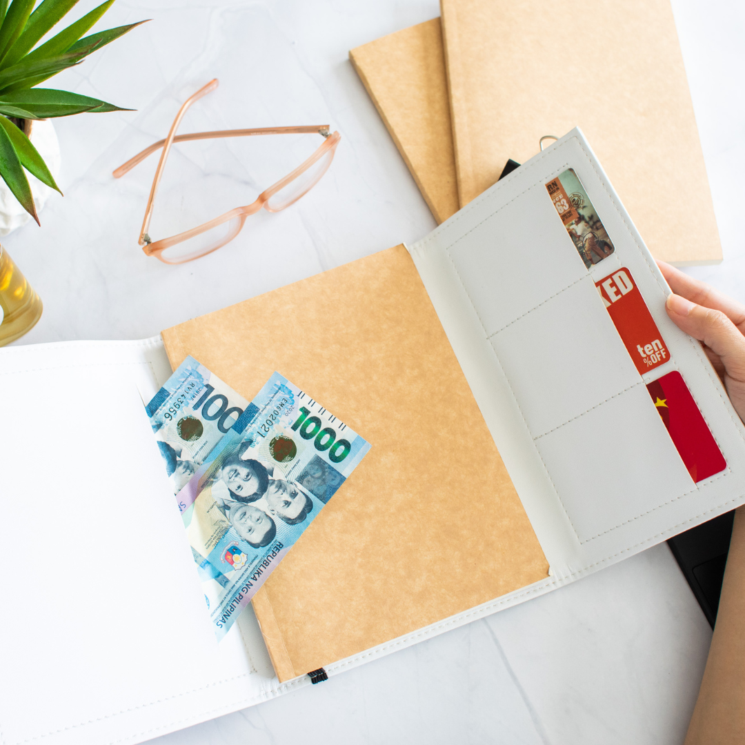 Peso bills peeking out of a compartment in a journal.
