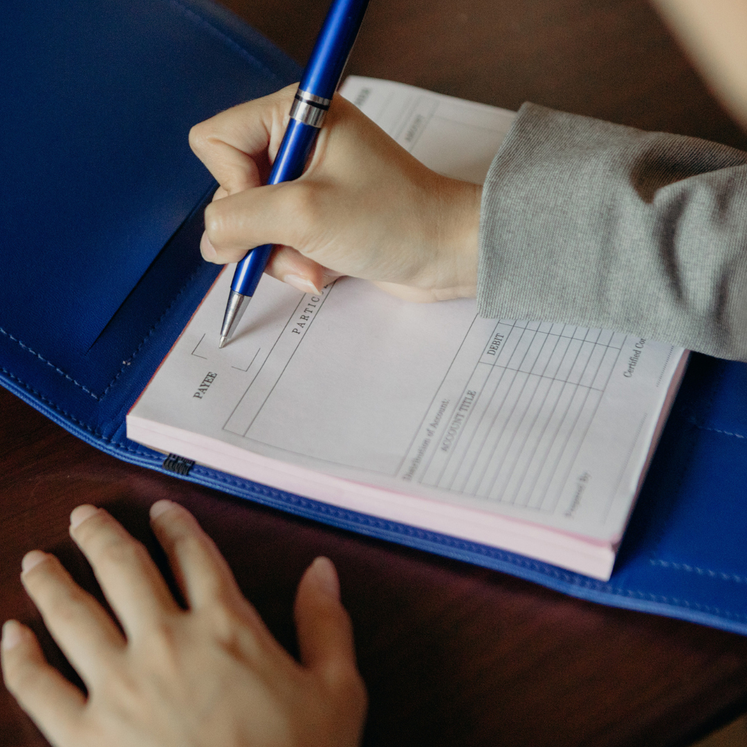 A person writing on a pad paper inside a blue sleeve.