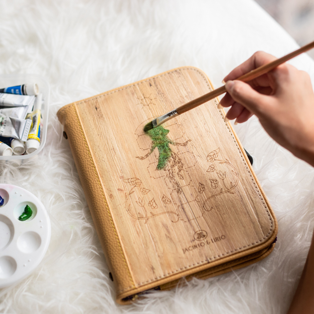 An artist painting green paint on the cover of a journal.