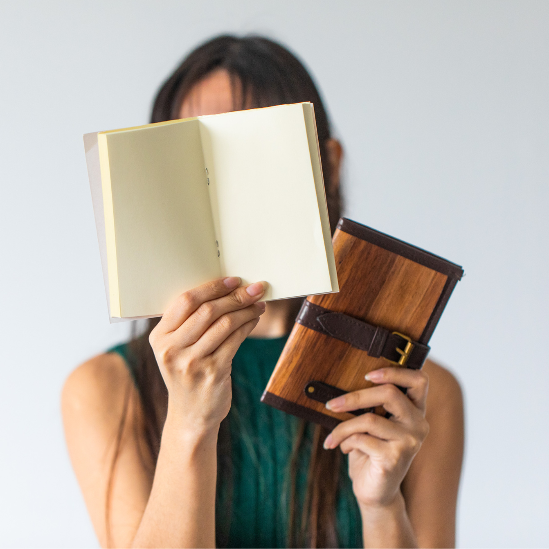 A woman holding up a notebook in front of her face.