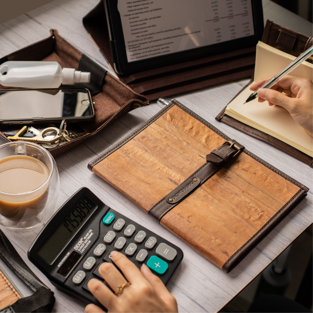 A person doing calculations while writing on a notebook.