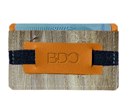 A card holder made out of vegan leather, with a strap attached to an orange piece of leather in front that has the BDO logo.