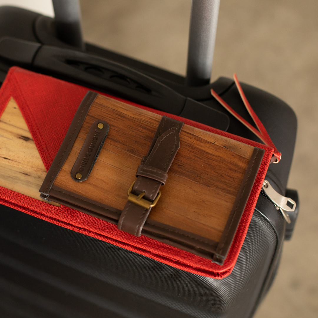 A journal resting on top a red wallet on top of a luggage.