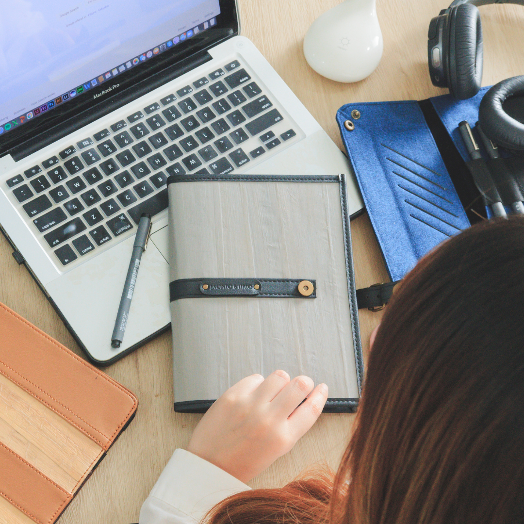 A woman holding a gray journal next to a blue tray.