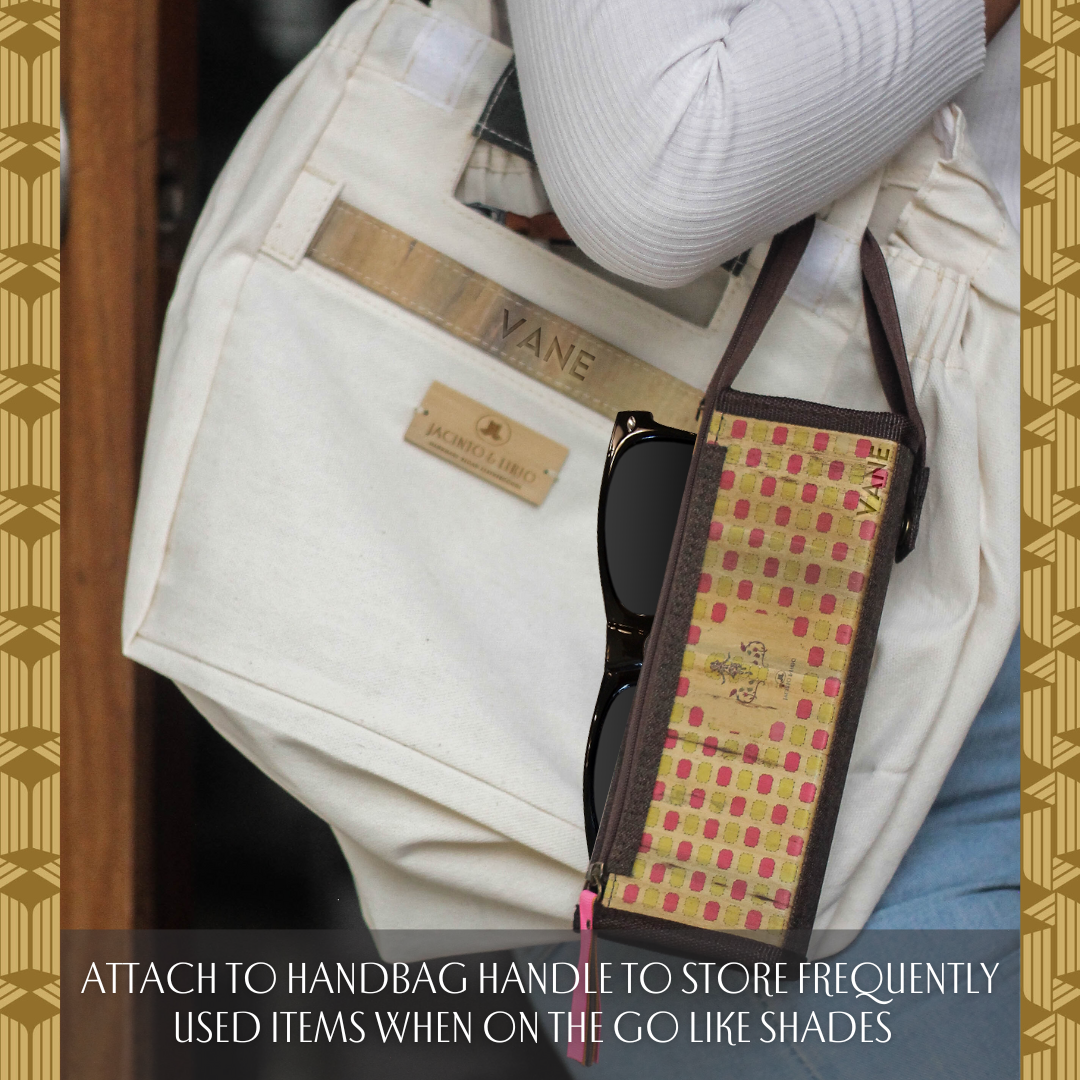 A brown pencil case looped around a white tote bags strap.
