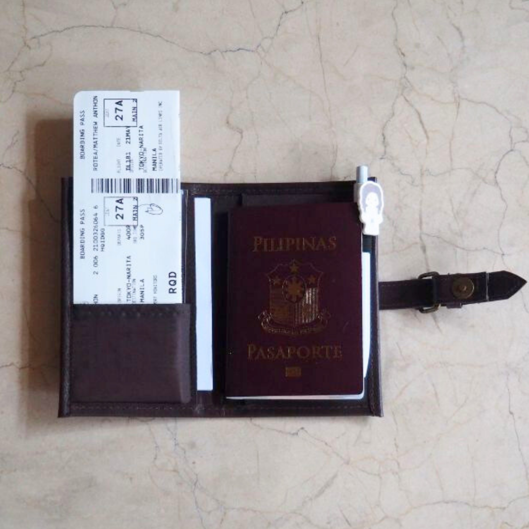 A philippine passport inside a brown passport holder.